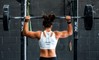 A woman working out in gym with a barbell