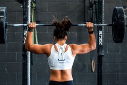 A woman working out in gym with a barbell